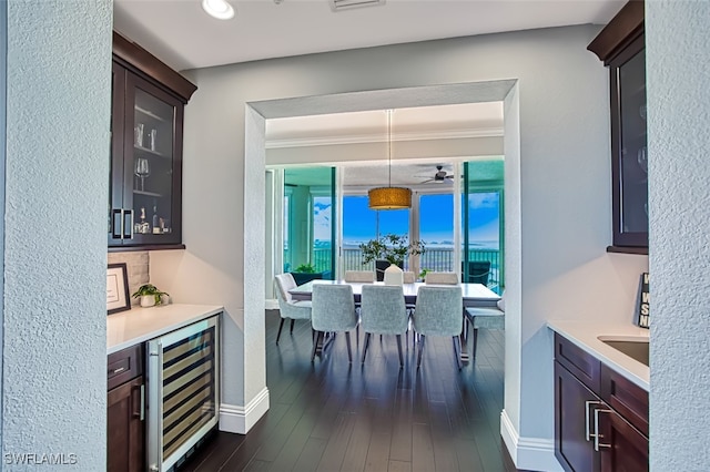 dining area with dark hardwood / wood-style floors, bar, beverage cooler, and crown molding