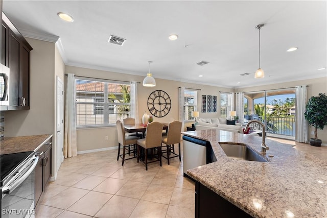 kitchen with sink, light stone counters, dark brown cabinets, appliances with stainless steel finishes, and pendant lighting