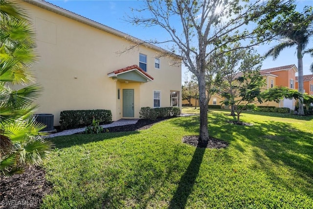 rear view of property featuring a yard and central AC unit