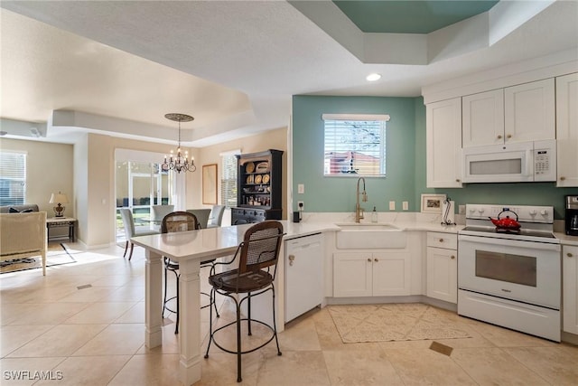 kitchen featuring a tray ceiling, sink, white appliances, and white cabinetry