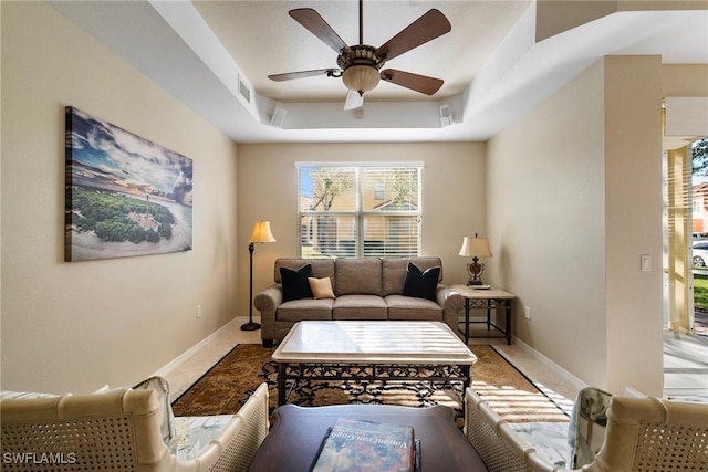 tiled living room featuring a raised ceiling and ceiling fan