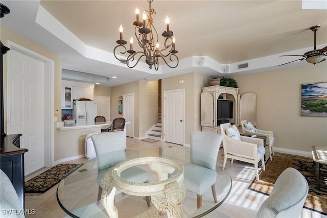 tiled dining room featuring a raised ceiling and ceiling fan with notable chandelier