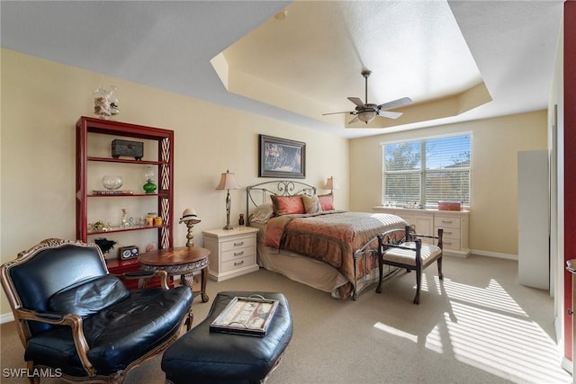 bedroom featuring light colored carpet, a raised ceiling, and ceiling fan