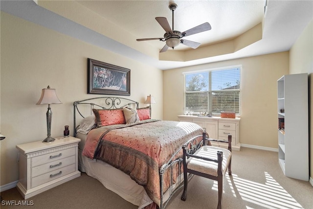 carpeted bedroom featuring ceiling fan and a tray ceiling