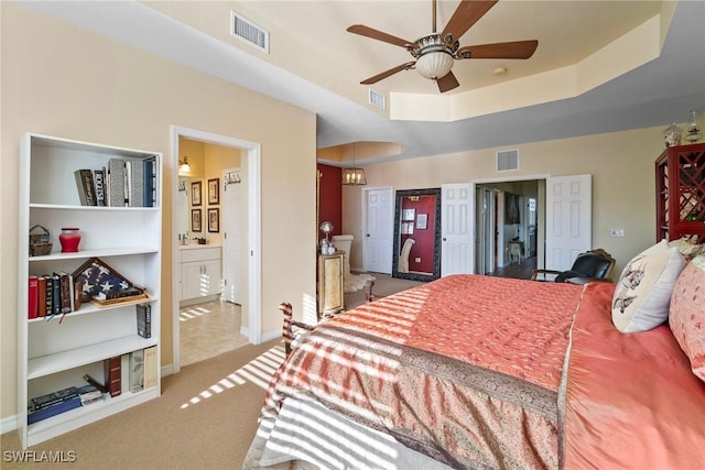 carpeted bedroom featuring sink, connected bathroom, and a tray ceiling