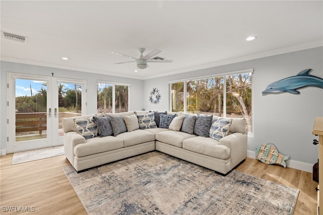 living room with ornamental molding, a healthy amount of sunlight, and light wood-type flooring