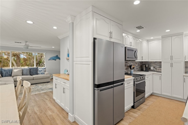 kitchen featuring tasteful backsplash, appliances with stainless steel finishes, light hardwood / wood-style floors, and white cabinets