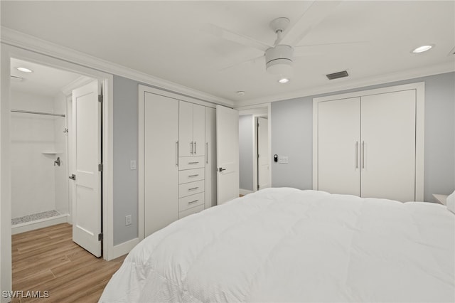 bedroom with crown molding, ceiling fan, two closets, and light wood-type flooring