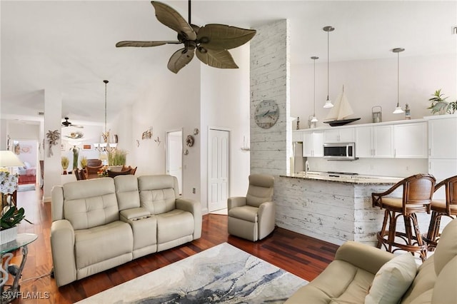 living room featuring ceiling fan, dark hardwood / wood-style flooring, and a towering ceiling