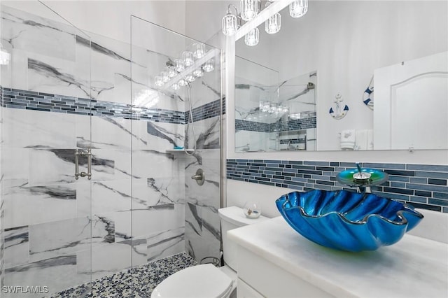 bathroom featuring vanity, tasteful backsplash, toilet, and tiled shower