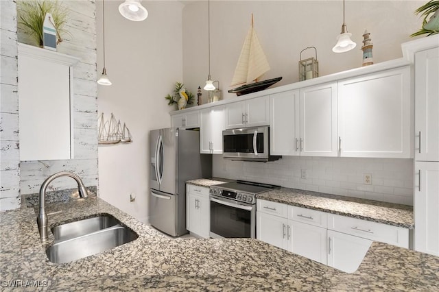 kitchen with appliances with stainless steel finishes, pendant lighting, white cabinetry, sink, and backsplash