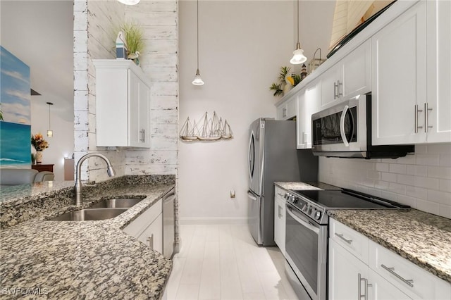 kitchen featuring white cabinetry, appliances with stainless steel finishes, decorative light fixtures, and sink