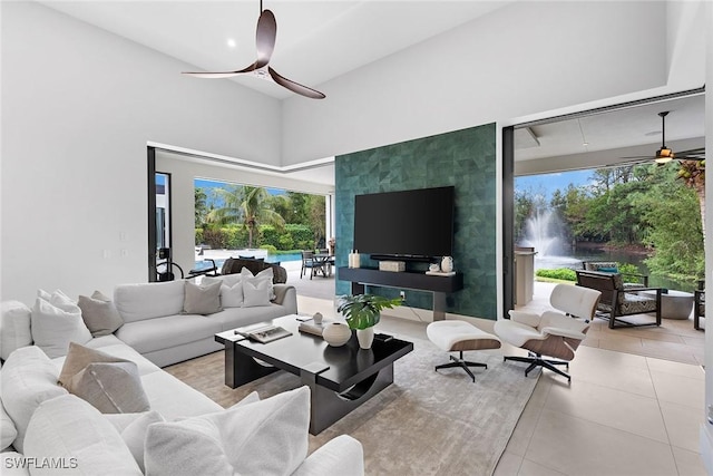 living room featuring a high ceiling, light tile patterned floors, and ceiling fan