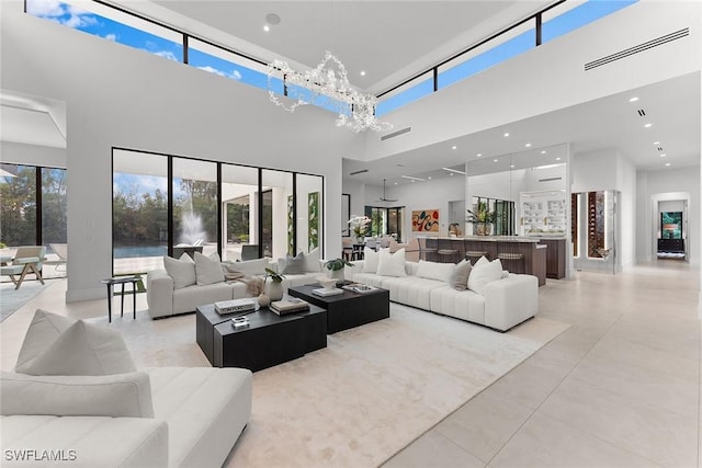 living room with an inviting chandelier, a towering ceiling, a healthy amount of sunlight, and light tile patterned floors