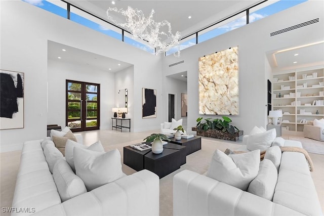 living room with a towering ceiling, an inviting chandelier, and french doors