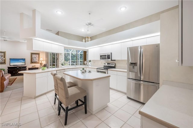 kitchen featuring a kitchen breakfast bar, stainless steel appliances, kitchen peninsula, and a kitchen island