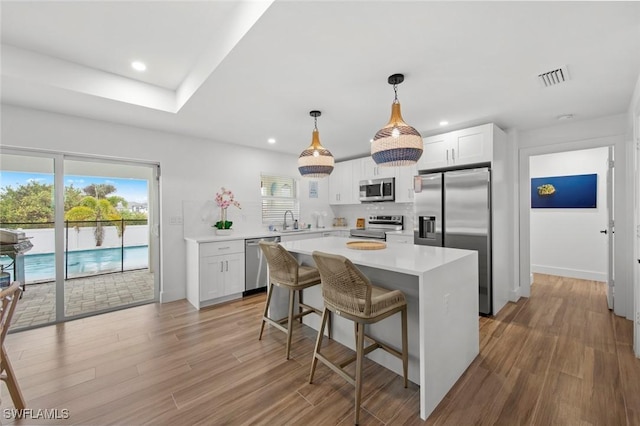 kitchen featuring white cabinetry, sink, a center island, light hardwood / wood-style floors, and stainless steel appliances