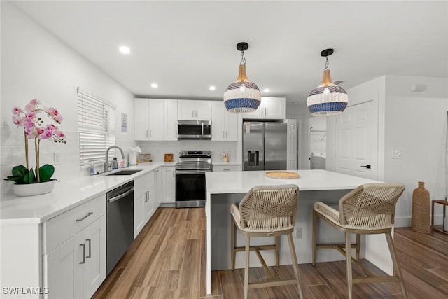 kitchen featuring stainless steel appliances, a center island, sink, and white cabinets