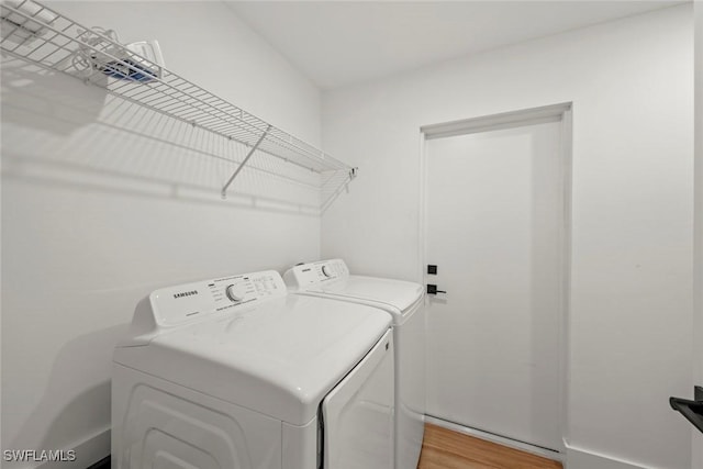 clothes washing area with hardwood / wood-style floors and washing machine and clothes dryer