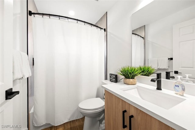 bathroom featuring vanity, hardwood / wood-style flooring, a shower with curtain, and toilet