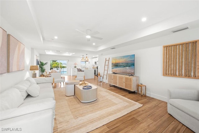 living room featuring a tray ceiling and ceiling fan