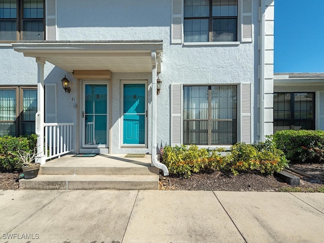 view of exterior entry featuring covered porch and stucco siding