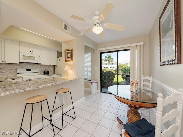 kitchen featuring light tile patterned floors, visible vents, backsplash, white microwave, and range