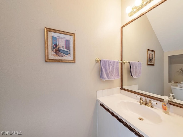 bathroom with vaulted ceiling, vanity, and toilet