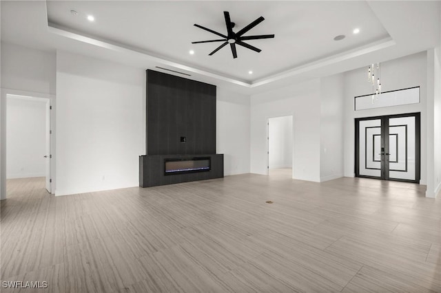 unfurnished living room featuring a towering ceiling, a large fireplace, and a tray ceiling