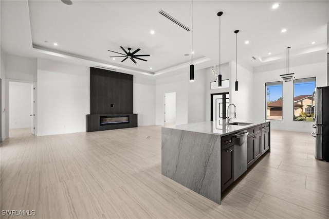 kitchen featuring sink, hanging light fixtures, stainless steel appliances, a spacious island, and a tray ceiling