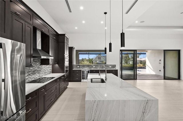 kitchen featuring sink, stainless steel fridge, hanging light fixtures, black electric stovetop, and wall chimney exhaust hood