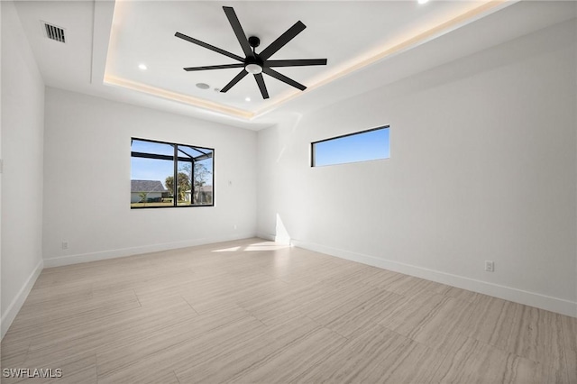 unfurnished room featuring a raised ceiling and ceiling fan