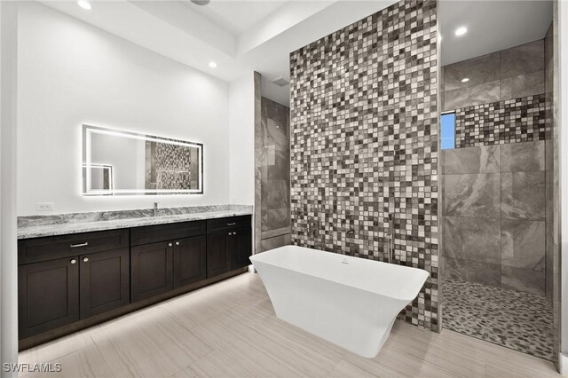 bathroom with vanity, separate shower and tub, and tile walls