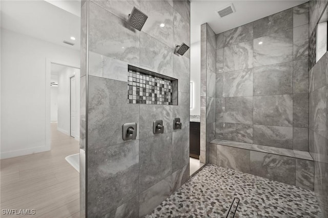 bathroom featuring hardwood / wood-style floors and a tile shower