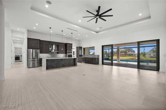 unfurnished living room with a towering ceiling, a raised ceiling, and ceiling fan