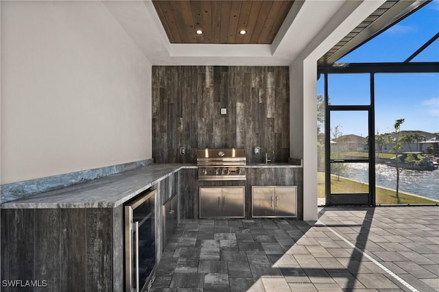 bar featuring wine cooler, dark brown cabinetry, a water view, wood ceiling, and a raised ceiling