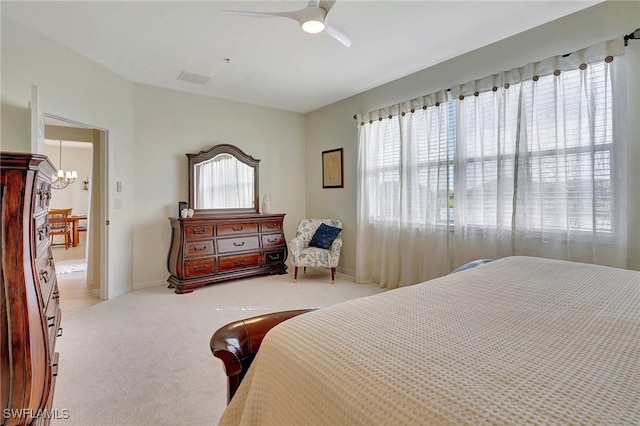 carpeted bedroom featuring ceiling fan with notable chandelier