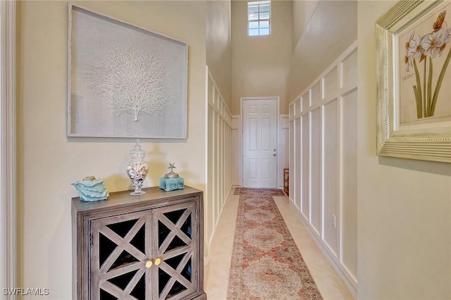 hall featuring a towering ceiling and light tile patterned flooring