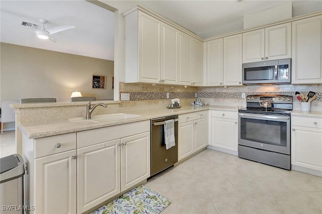 kitchen with sink, stainless steel appliances, tasteful backsplash, light stone countertops, and kitchen peninsula