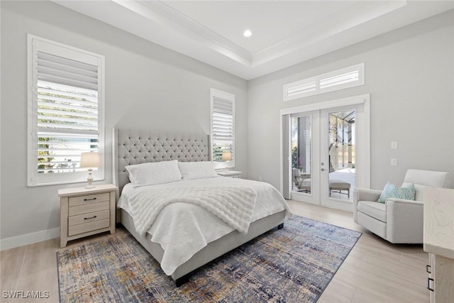 bedroom with french doors, a raised ceiling, light wood-type flooring, and access to outside