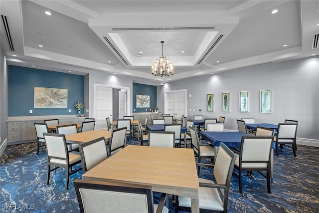 dining area with a notable chandelier, a raised ceiling, and dark colored carpet