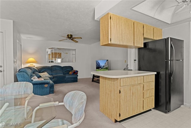 kitchen featuring black refrigerator, kitchen peninsula, ceiling fan, and light brown cabinets