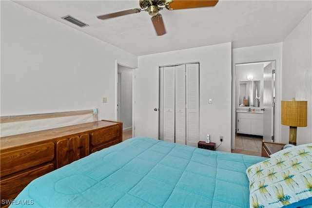 tiled bedroom with connected bathroom, ceiling fan, and a closet