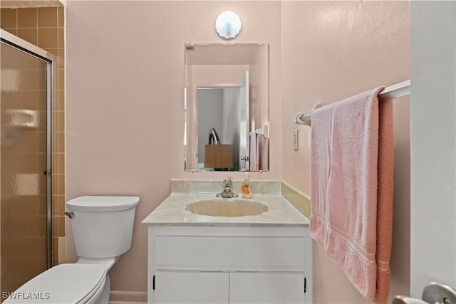 bathroom with vanity, toilet, and a shower with door