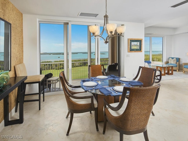 dining area featuring a water view and an inviting chandelier