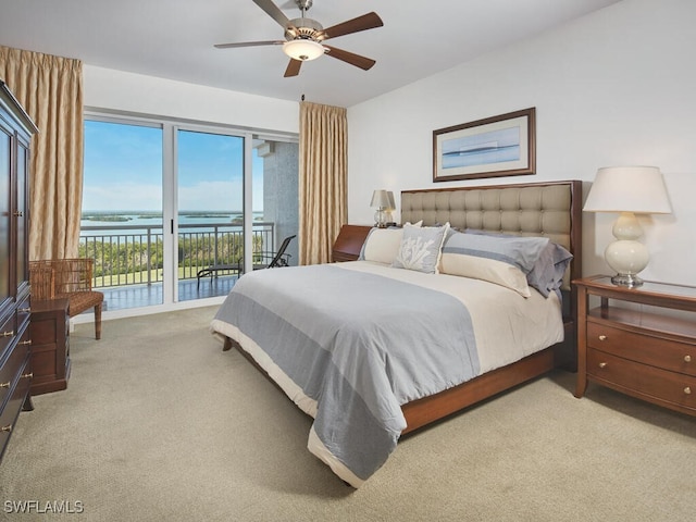 carpeted bedroom featuring access to outside, ceiling fan, and a water view