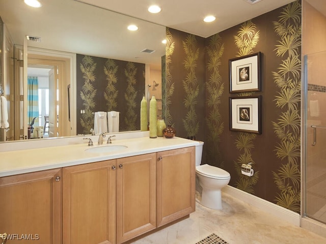 bathroom featuring a shower with door, vanity, and toilet