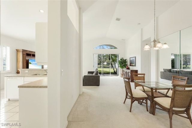 carpeted dining space with an inviting chandelier, sink, plenty of natural light, and high vaulted ceiling