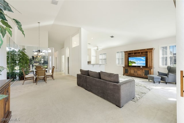 carpeted living room with high vaulted ceiling and a chandelier