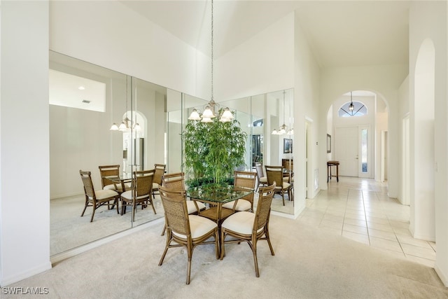 dining space featuring a chandelier, light carpet, and a high ceiling